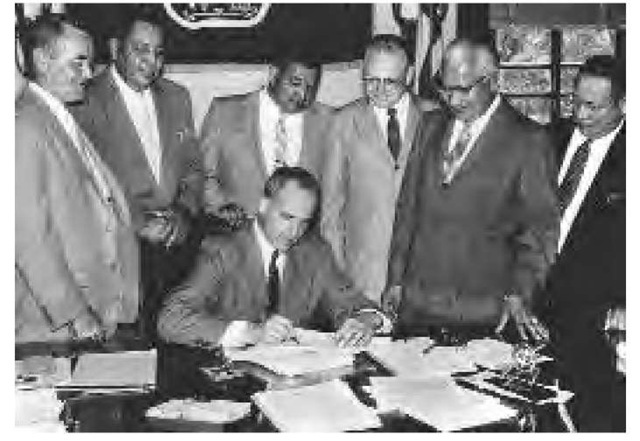 Governor Nelson of Wisconsin is shown signing a bill that created Menominee County, July 31, 1959. After the Menominee signed this agreement, their community fell upon hard times.