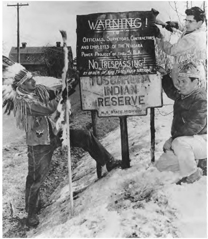 In 1958, the New York State Power Authority planned a reservoir that would flood the Tuscarora Reservation in Niagara County, New York. As part of a public and legal protest, William Rickard (left) and Wallace "Mad Bear" Anderson (right) warn officials to leave their land alone.