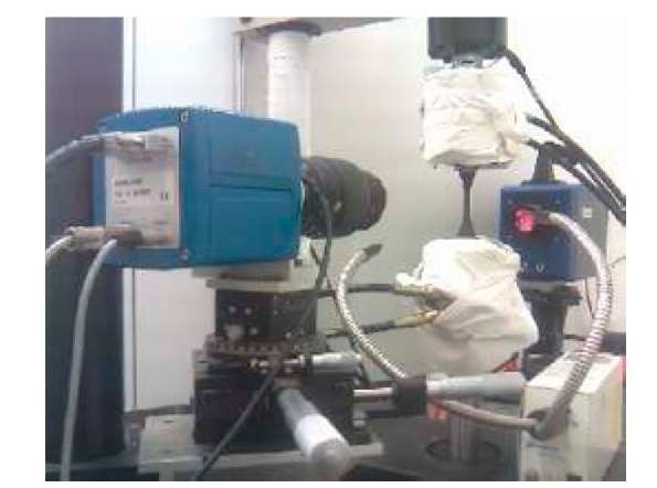 Experimental set-up. (Front): CCD camera and cold light sources, (back): IRFPA camera. The grips and columns of the testing machine are roughly wrapped to avoid parasitic reflection 
