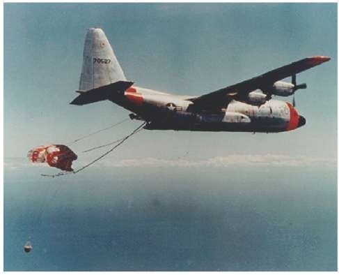 A U.S. Air Force C-119, and later, a C-130 (shown here) modified with poles, lines, and winches extending from the rear cargo door captures a capsule ejected from a Discoverer satellite. Reportedly, this was considered by some to be the least likely part of the whole process—catching a satellite in midair.